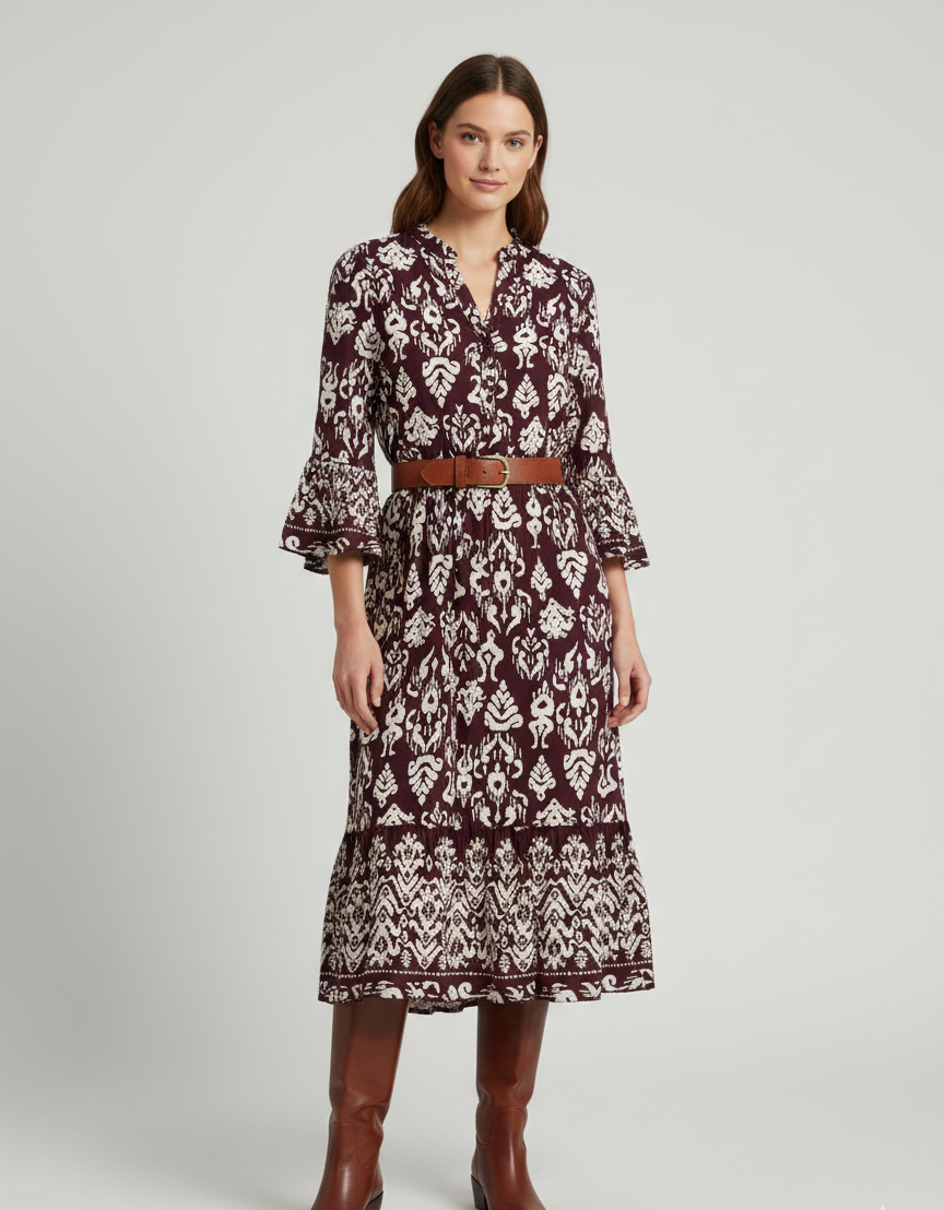 Woman wearing a patterned dress with a belt and boots on a white background