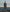 Woman in a long floral dress and cap standing on rocks by the ocean