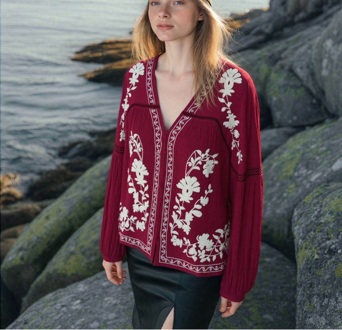 Woman wearing a red embroidered blouse with buttons  by a coastal landscape